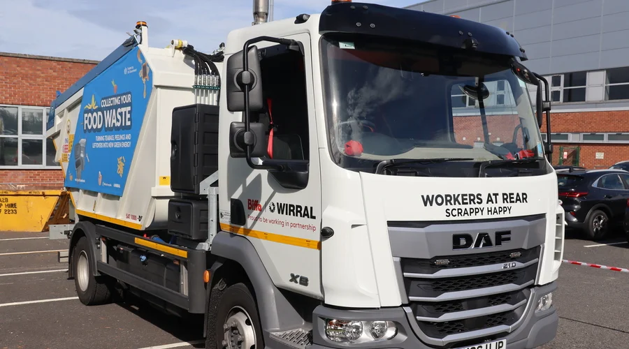 A white DAF food waste lorry with the name Scrappy Happy printed under the windscreen and a blue Collecting Your Food Waste panel on its side